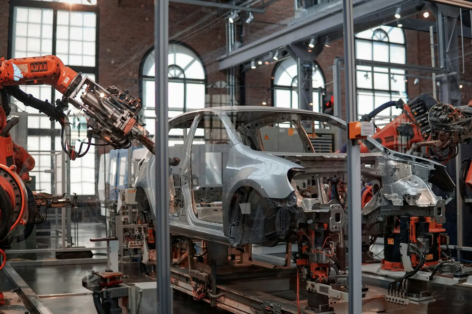 Orangefarbene Industrieroboter an einer Fertigungslinie in einer hohen Halle, Symbolbild